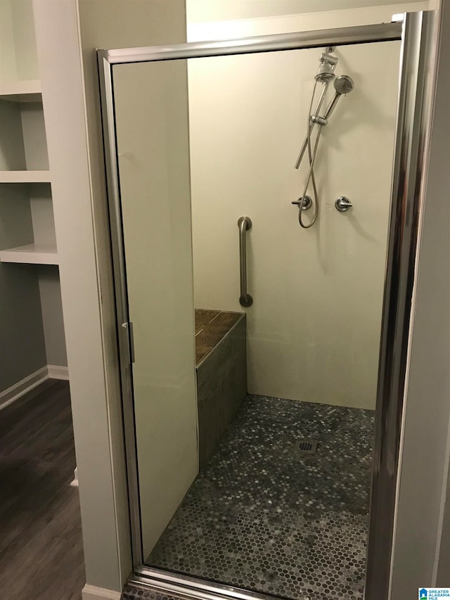 bathroom with hardwood / wood-style flooring and a shower with shower door