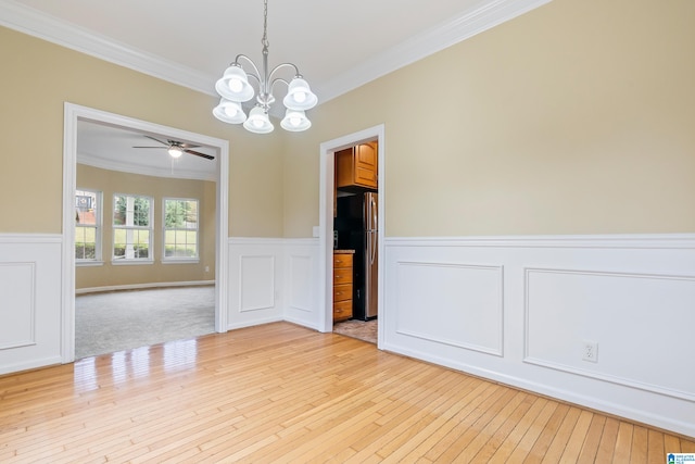 unfurnished room with light carpet, ceiling fan with notable chandelier, and crown molding