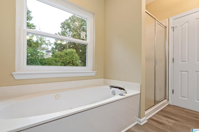 bathroom featuring wood-type flooring and shower with separate bathtub