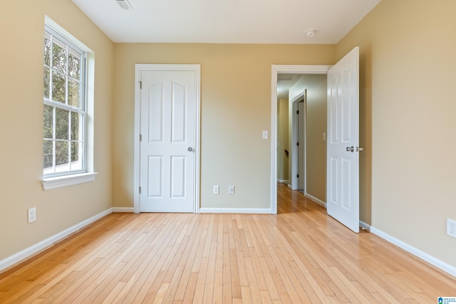 unfurnished bedroom featuring multiple windows and light hardwood / wood-style flooring