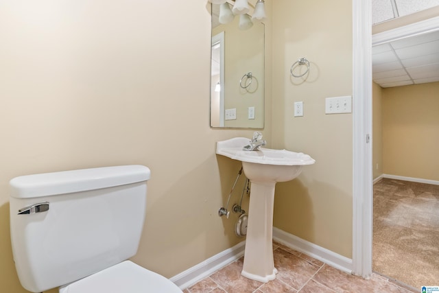 bathroom featuring a drop ceiling, tile patterned flooring, and toilet