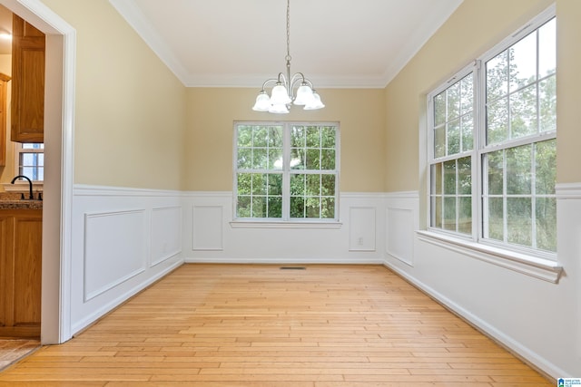 unfurnished dining area with light hardwood / wood-style floors, plenty of natural light, a chandelier, and crown molding