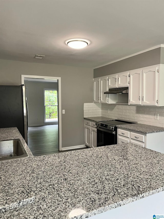 kitchen featuring wood-type flooring, stainless steel fridge, white cabinets, black / electric stove, and light stone counters