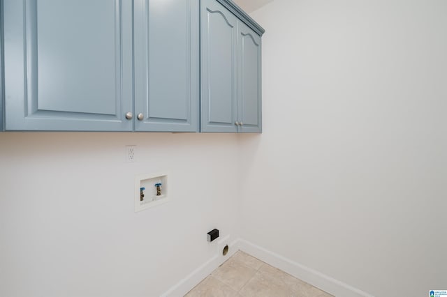 washroom with light tile patterned flooring, washer hookup, and cabinets