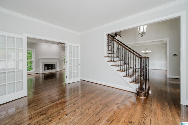 unfurnished living room with ornamental molding, an inviting chandelier, a premium fireplace, and dark hardwood / wood-style flooring