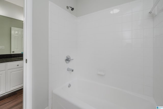 bathroom featuring wood-type flooring, tiled shower / bath, and vanity