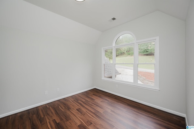 empty room featuring vaulted ceiling and dark hardwood / wood-style floors