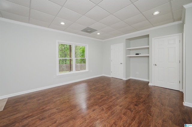 unfurnished bedroom featuring a drop ceiling, crown molding, and dark hardwood / wood-style flooring