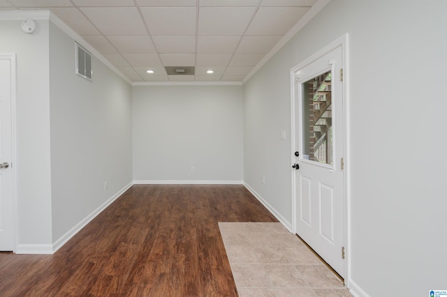 unfurnished room featuring ornamental molding, a drop ceiling, and hardwood / wood-style flooring