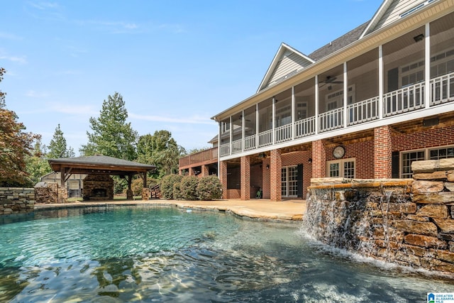 view of swimming pool featuring a patio, a gazebo, ceiling fan, a sunroom, and pool water feature