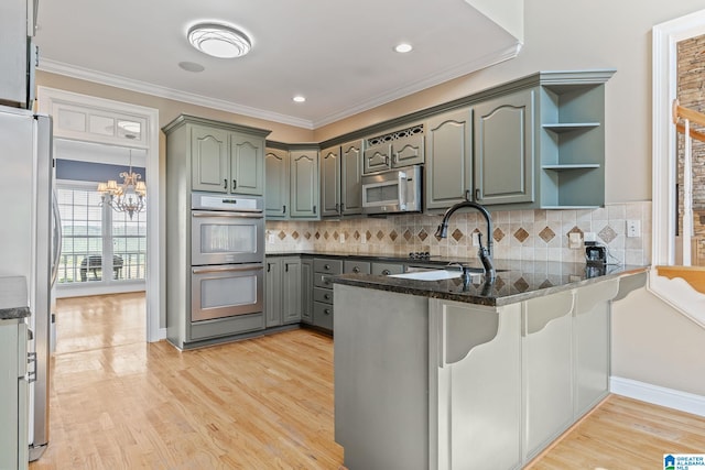 kitchen featuring a chandelier, kitchen peninsula, appliances with stainless steel finishes, and light hardwood / wood-style floors