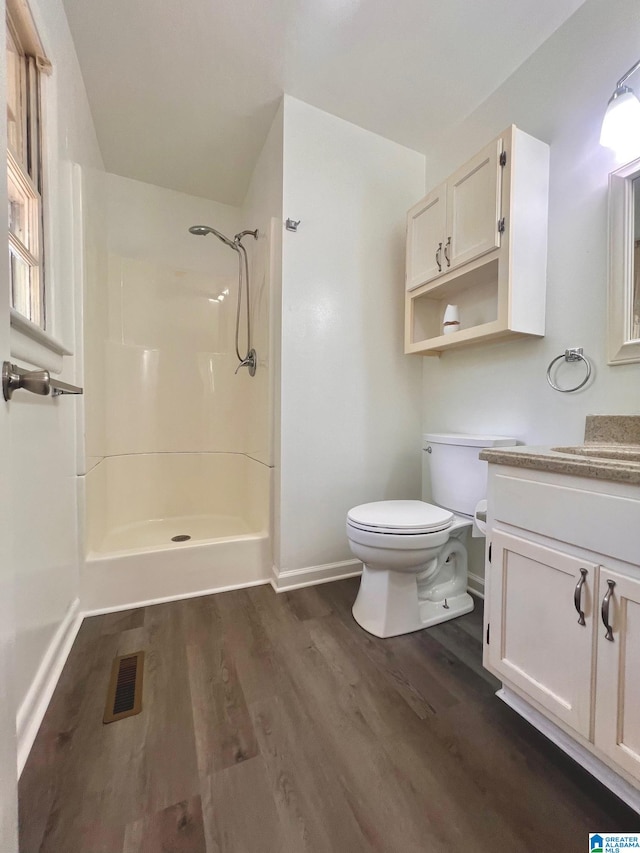 bathroom with walk in shower, vanity, hardwood / wood-style floors, and toilet