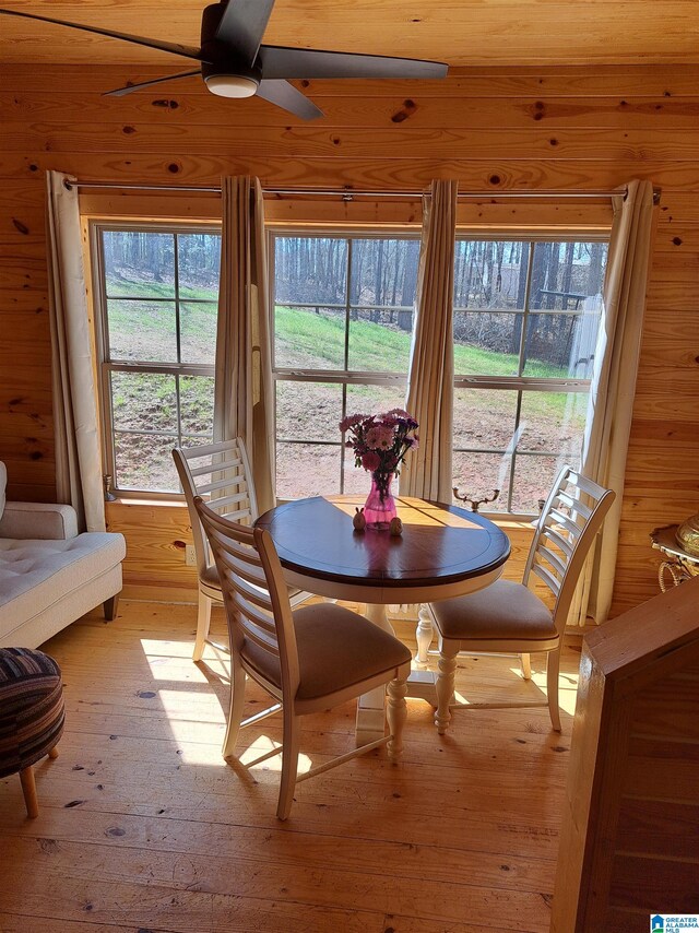 dining area featuring wood walls, ceiling fan, and light hardwood / wood-style flooring