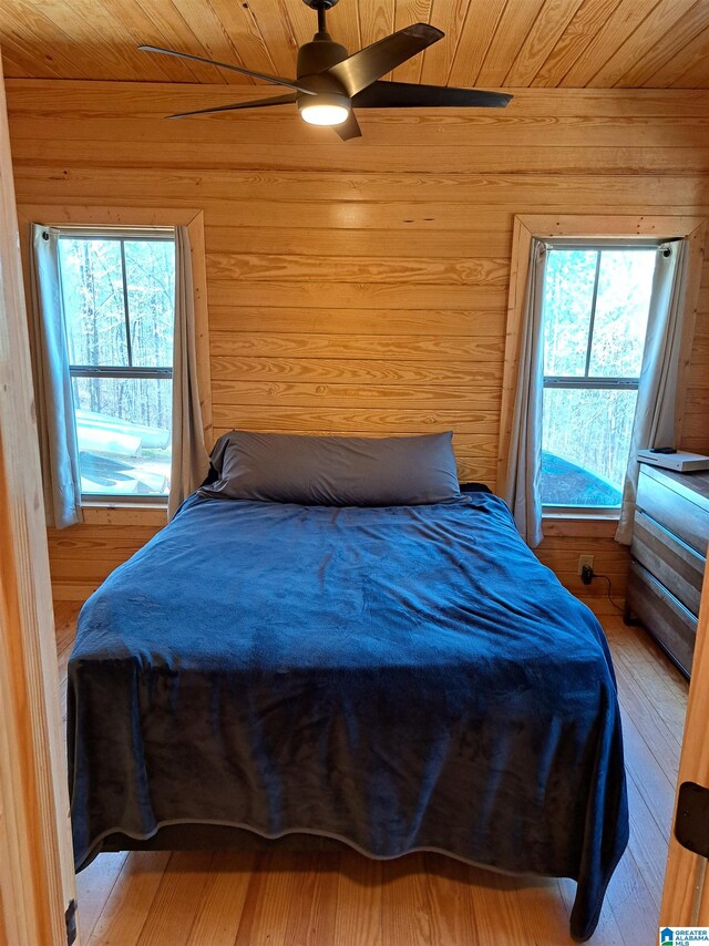 bedroom with ceiling fan, light hardwood / wood-style flooring, wood walls, and wooden ceiling