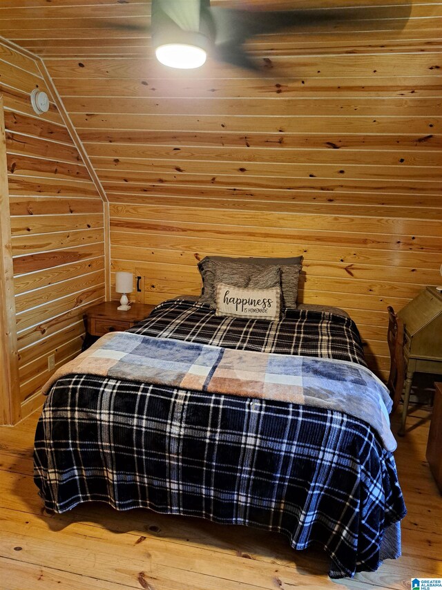 bedroom with hardwood / wood-style flooring, lofted ceiling, and wooden walls