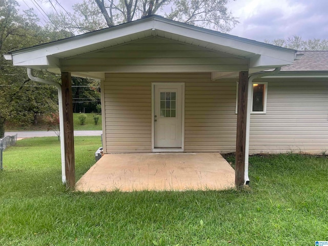 entrance to property featuring a lawn and a patio area