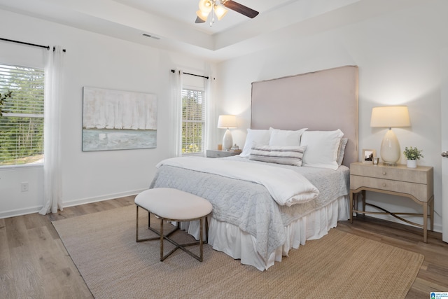 bedroom featuring ceiling fan, light hardwood / wood-style floors, and multiple windows