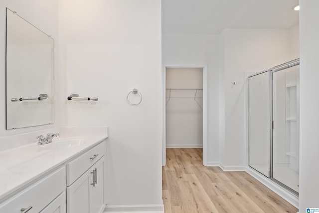 bathroom featuring walk in shower, wood-type flooring, and vanity