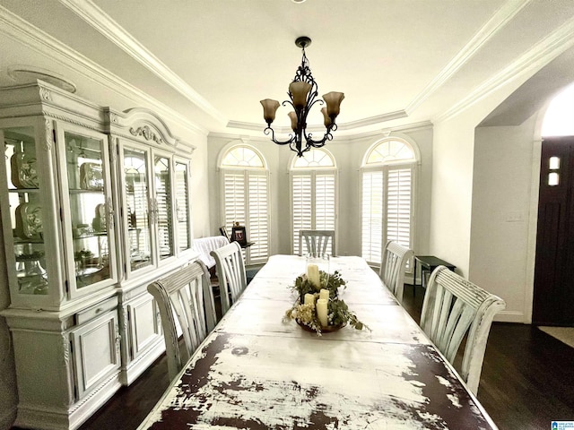 dining space with a tray ceiling, dark hardwood / wood-style floors, ornamental molding, and a chandelier