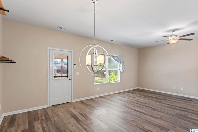 interior space featuring ceiling fan with notable chandelier, dark wood-type flooring, and a healthy amount of sunlight