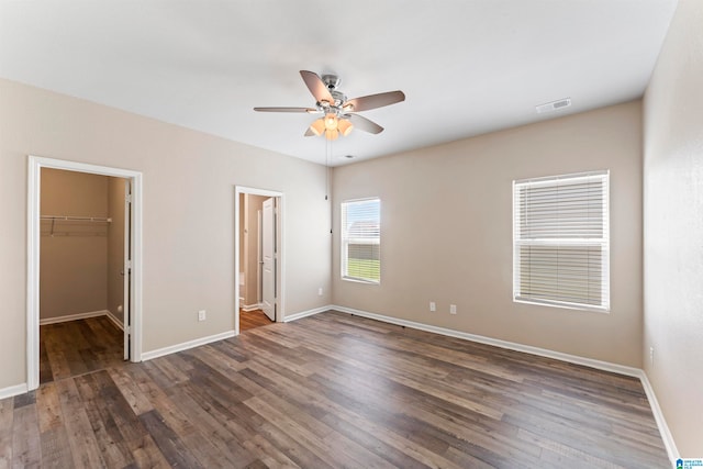 unfurnished bedroom with ceiling fan, a closet, dark hardwood / wood-style flooring, and a spacious closet