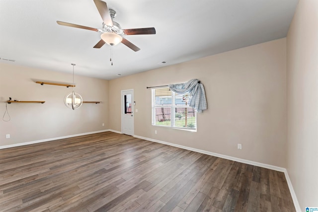 unfurnished room featuring ceiling fan with notable chandelier and dark wood-type flooring