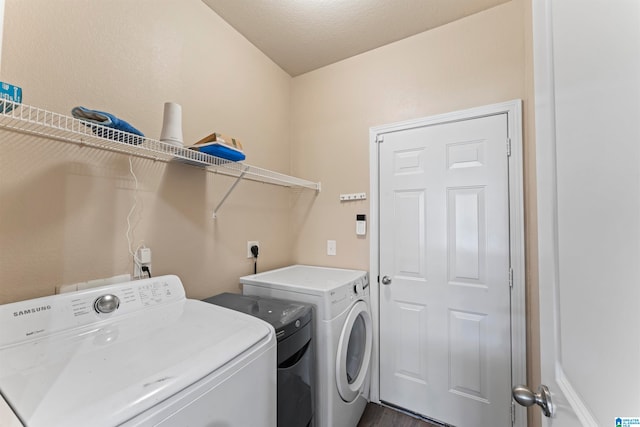 laundry room with washing machine and clothes dryer, a textured ceiling, and dark hardwood / wood-style floors