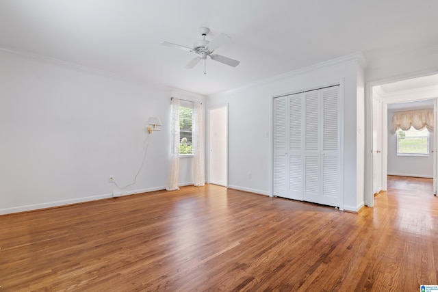 unfurnished bedroom with wood-type flooring, ornamental molding, multiple windows, and ceiling fan