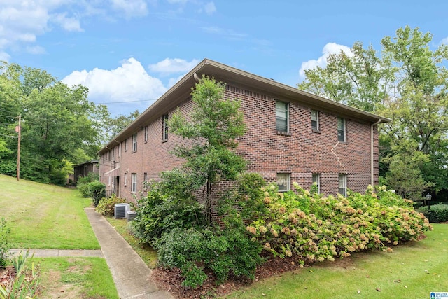 view of side of home featuring central AC unit and a yard