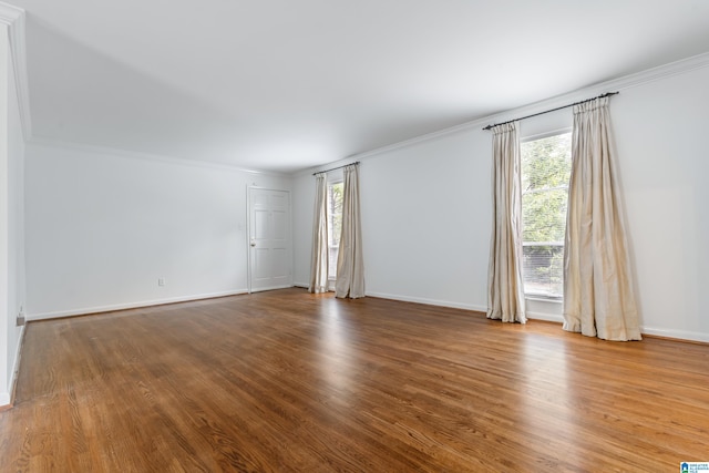 empty room with hardwood / wood-style flooring and crown molding