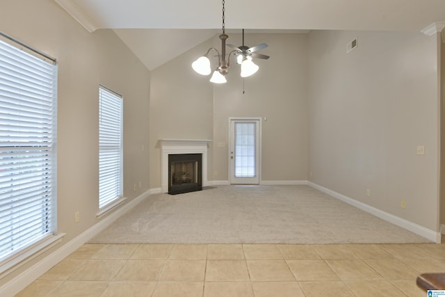 unfurnished living room with light colored carpet, ceiling fan with notable chandelier, ornamental molding, and a wealth of natural light