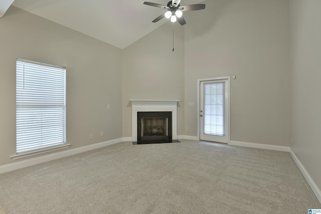 unfurnished living room with high vaulted ceiling, ceiling fan, and light carpet