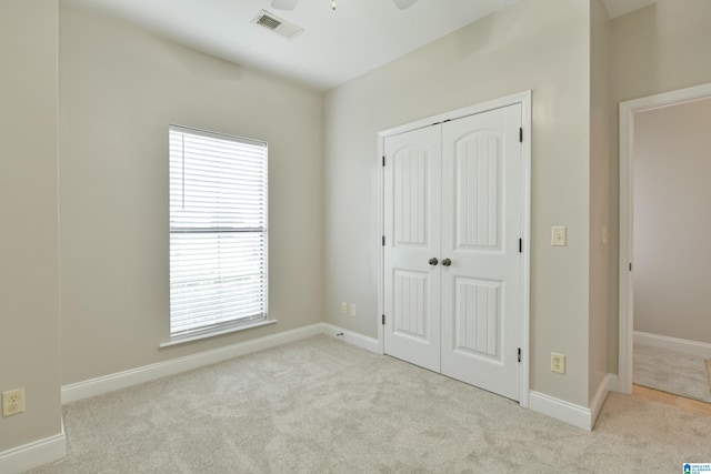 unfurnished bedroom with light colored carpet and a closet