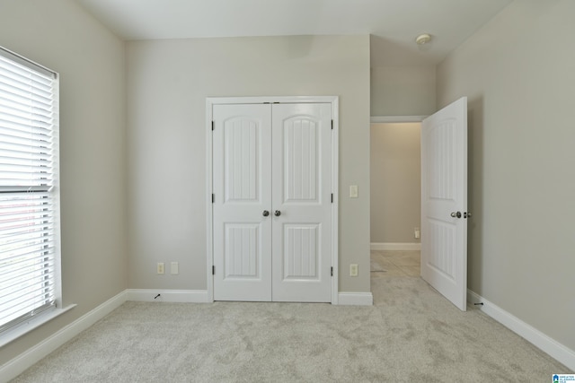 unfurnished bedroom featuring light colored carpet and a closet