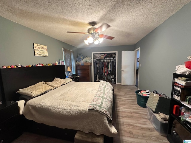 bedroom with a spacious closet, a closet, light wood-type flooring, a textured ceiling, and ceiling fan