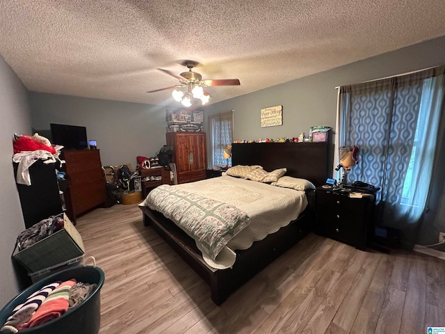 bedroom with wood-type flooring, a textured ceiling, and ceiling fan