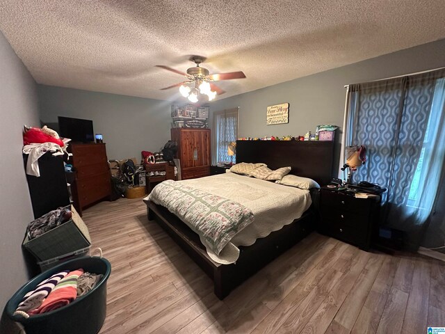 bedroom with light wood-type flooring, ceiling fan, and a textured ceiling