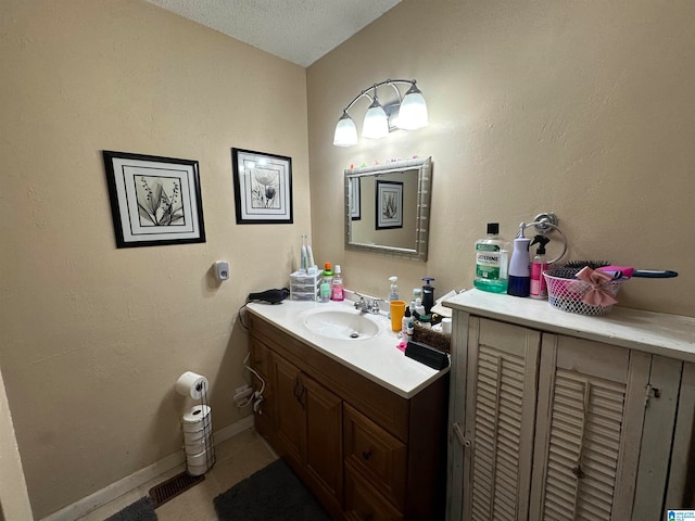 bathroom with a textured ceiling, tile patterned flooring, and vanity