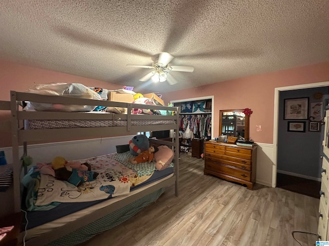 bedroom with a textured ceiling, ceiling fan, light hardwood / wood-style flooring, and a closet