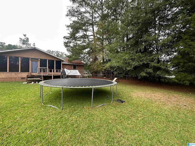 view of yard featuring a trampoline and a wooden deck