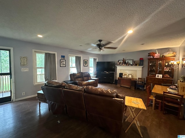 living room with a textured ceiling, dark wood-type flooring, and ceiling fan