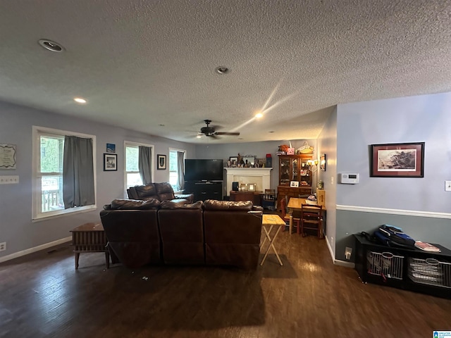 living room featuring a textured ceiling, dark hardwood / wood-style floors, and ceiling fan