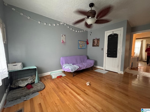 bedroom featuring ceiling fan, hardwood / wood-style flooring, and a textured ceiling