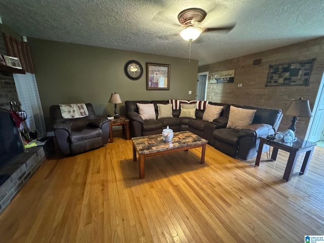 living room with a textured ceiling, wood-type flooring, wooden walls, and ceiling fan