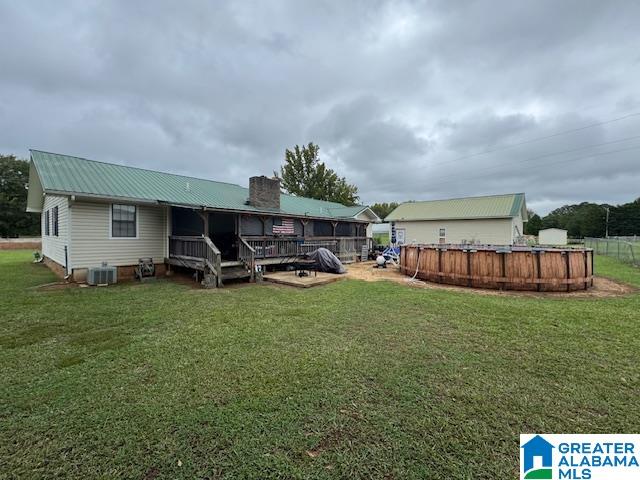 rear view of house featuring a lawn, a swimming pool side deck, and central air condition unit