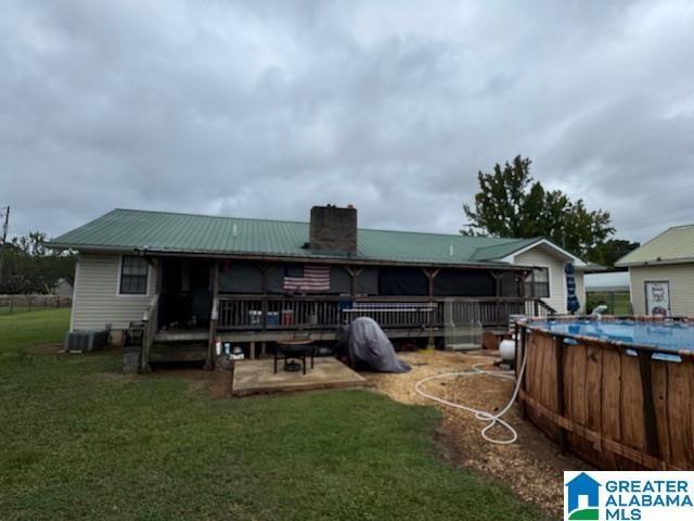 back of property featuring a pool side deck and a yard