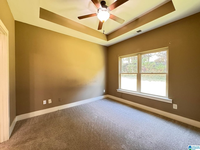 spare room featuring ceiling fan, a tray ceiling, and carpet flooring