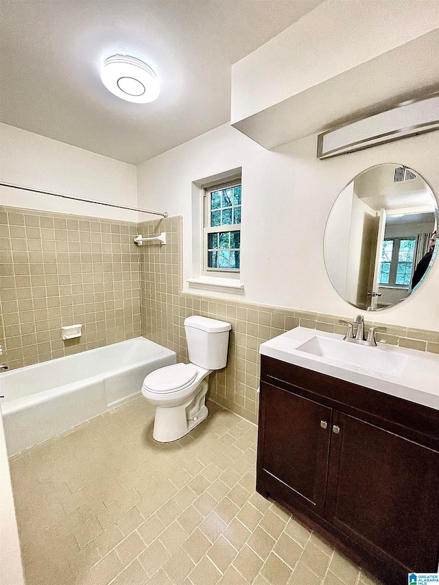 full bathroom featuring tile walls, tile patterned floors, vanity, tiled shower / bath, and toilet