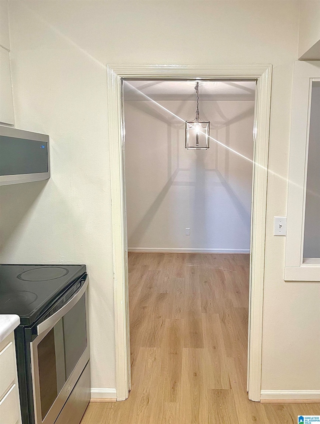 interior space with stainless steel range with electric stovetop, light hardwood / wood-style floors, and decorative light fixtures