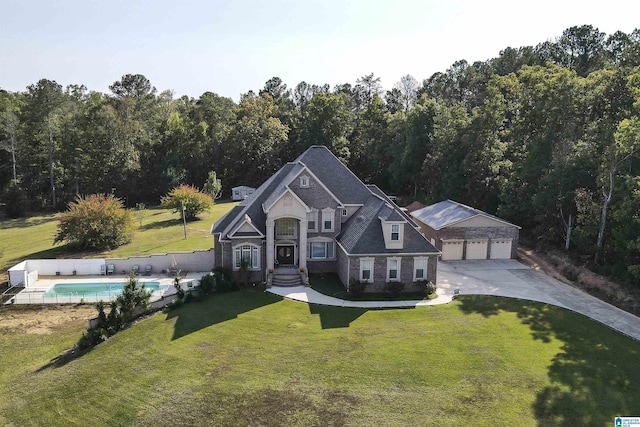 view of front of house featuring a garage, an outdoor pool, a forest view, and a front lawn